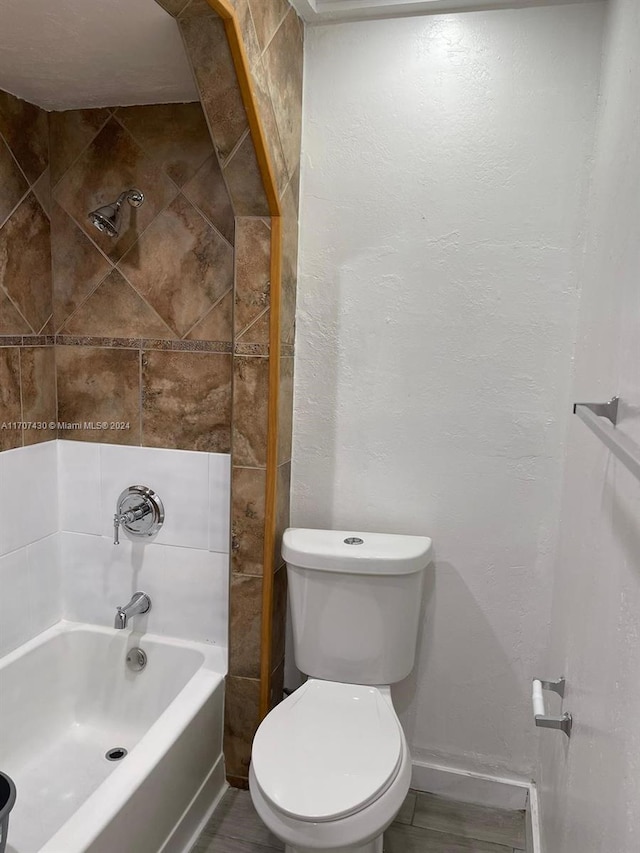 bathroom with tiled shower / bath combo and toilet