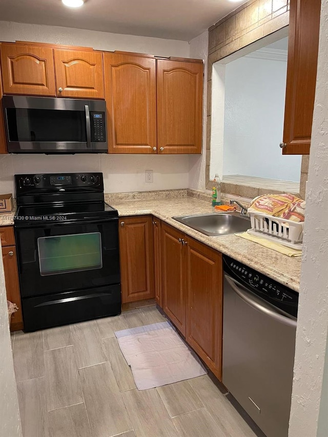 kitchen with light stone counters, light wood-type flooring, sink, and appliances with stainless steel finishes