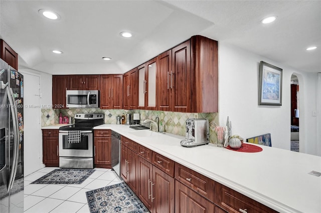 kitchen with appliances with stainless steel finishes, backsplash, light tile patterned floors, and sink