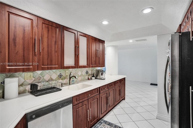 kitchen featuring refrigerator, backsplash, sink, dishwasher, and light tile patterned flooring