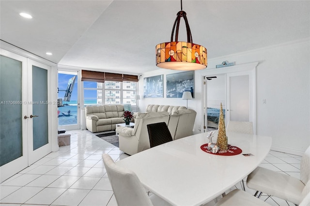 tiled dining room with expansive windows, a water view, ornamental molding, and french doors