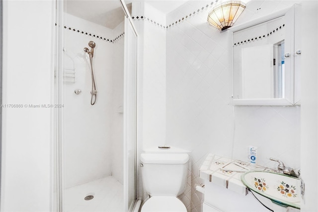 bathroom featuring a tile shower, vanity, toilet, and tile walls