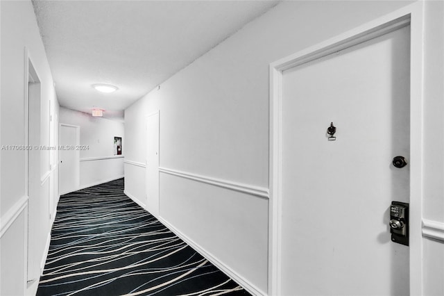 hallway with carpet flooring and a textured ceiling