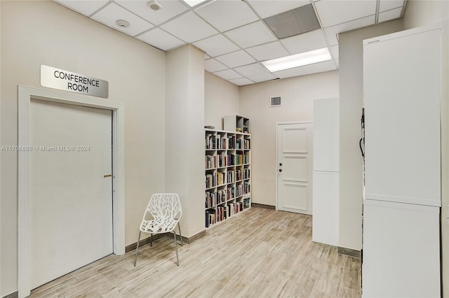 interior space featuring a drop ceiling and light hardwood / wood-style flooring