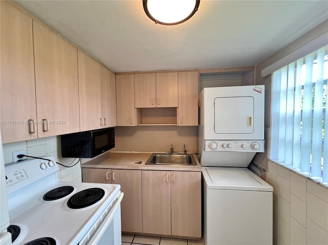 laundry area featuring stacked washing maching and dryer, sink, and light tile patterned floors