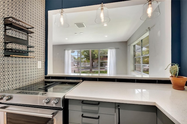 kitchen featuring stainless steel range, backsplash, gray cabinets, and a wealth of natural light