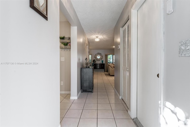 corridor with light tile patterned flooring and a textured ceiling