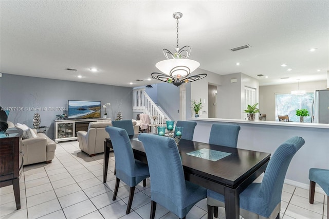 tiled dining space featuring a chandelier and a textured ceiling