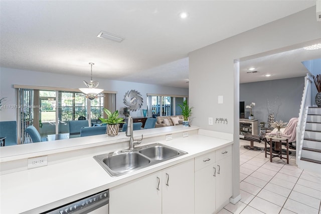 kitchen featuring kitchen peninsula, stainless steel dishwasher, sink, pendant lighting, and white cabinetry