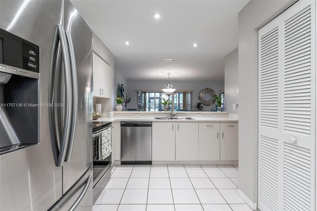 kitchen with sink, white cabinets, stainless steel appliances, and decorative light fixtures