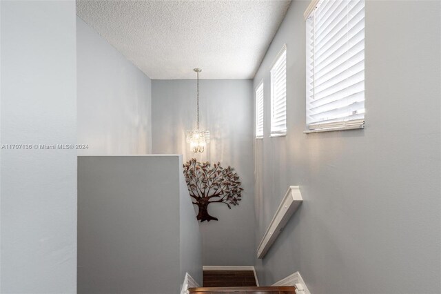 stairs featuring a notable chandelier and a textured ceiling