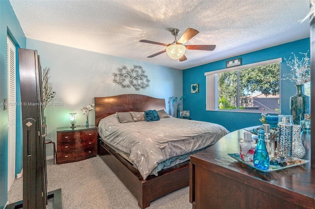 carpeted bedroom with ceiling fan and a textured ceiling