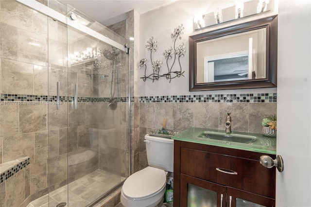 bathroom featuring vanity, toilet, a shower with shower door, and tile walls