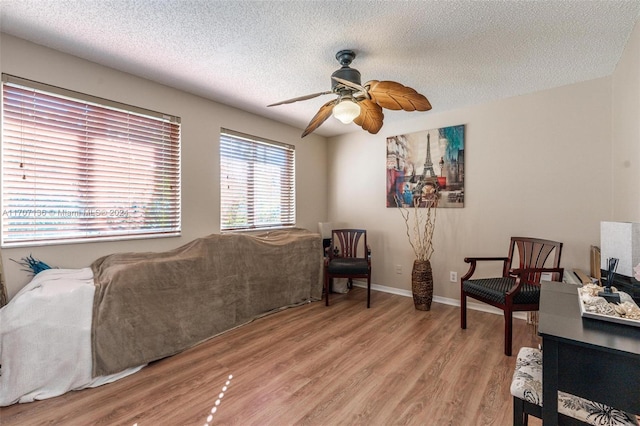 living room with a textured ceiling, light hardwood / wood-style flooring, and ceiling fan