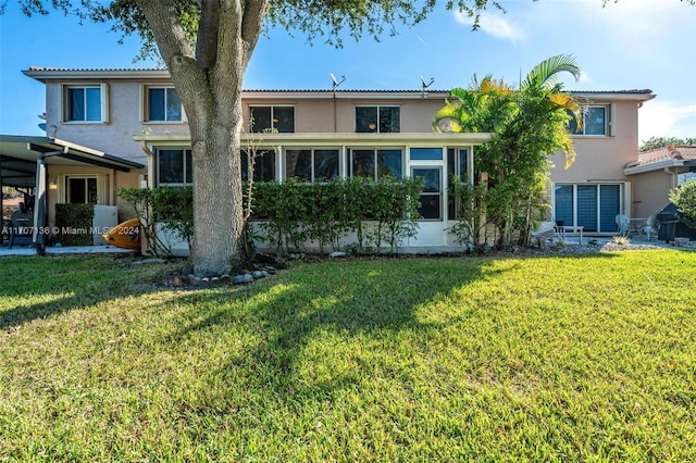 back of property with a yard and a sunroom