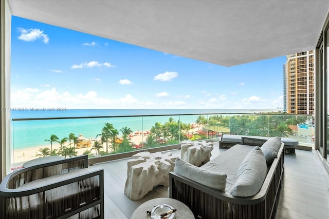 balcony featuring an outdoor living space, a water view, and a beach view