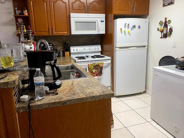 kitchen featuring washer / dryer, white appliances, backsplash, and light tile patterned floors