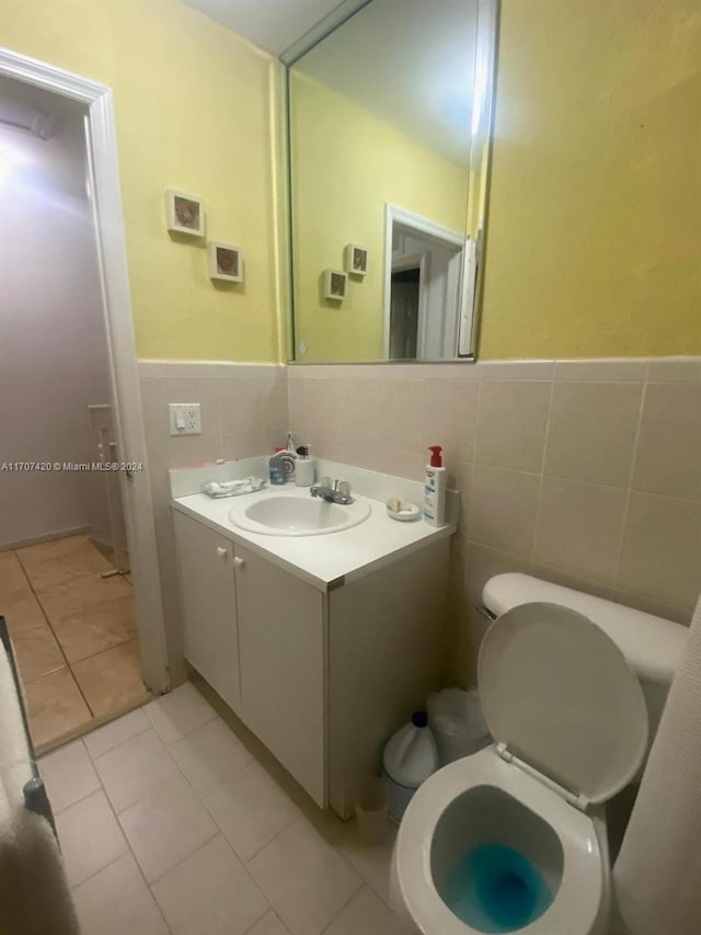 bathroom with tile patterned floors, vanity, tile walls, and toilet