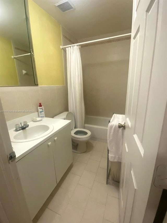 full bathroom featuring vanity, backsplash, toilet, tile walls, and shower / tub combo