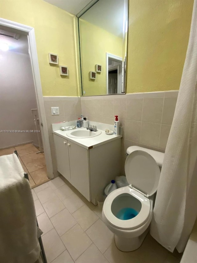 bathroom featuring toilet, vanity, tile patterned floors, and tile walls