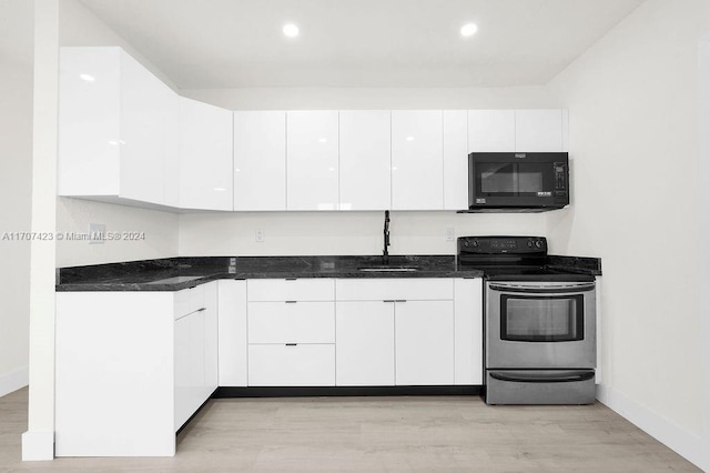 kitchen featuring dark stone counters, stainless steel electric stove, sink, light hardwood / wood-style flooring, and white cabinetry