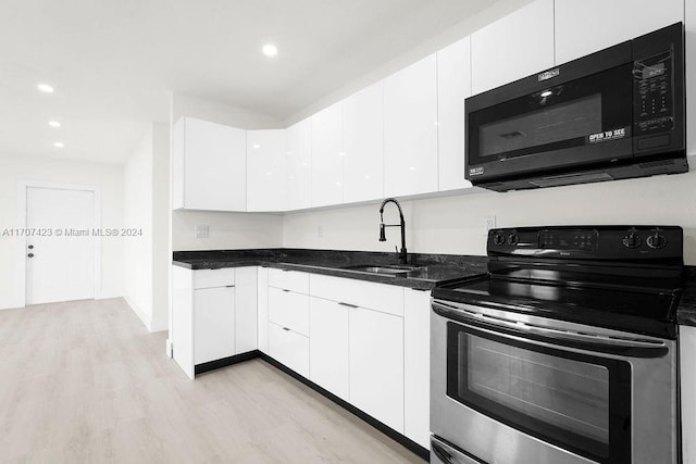 kitchen with white cabinets, sink, light hardwood / wood-style flooring, dark stone countertops, and stainless steel electric range oven