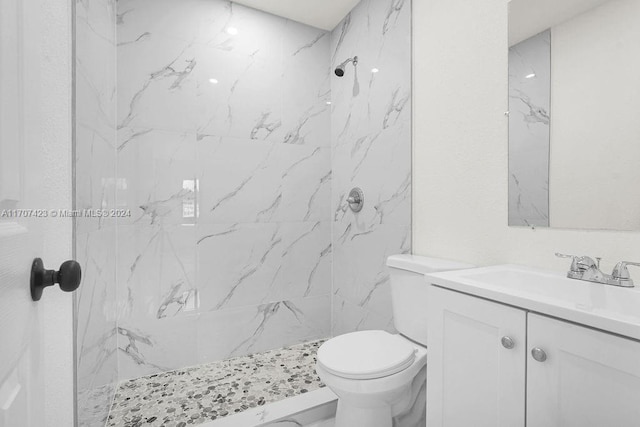 bathroom with a tile shower, vanity, and toilet