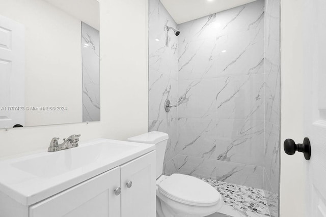 bathroom with tiled shower, vanity, and toilet