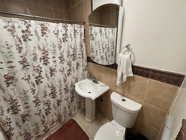 bathroom with toilet, tile patterned floors, tile walls, and walk in shower