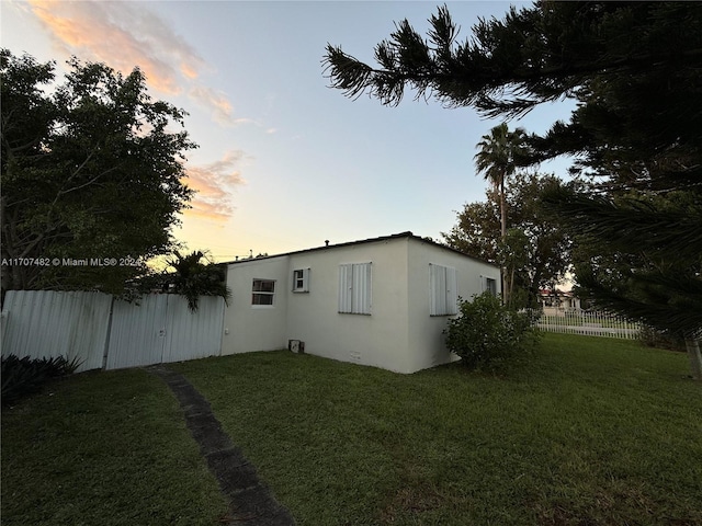 property exterior at dusk with a lawn