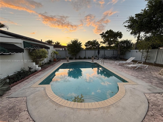 pool at dusk with a patio area