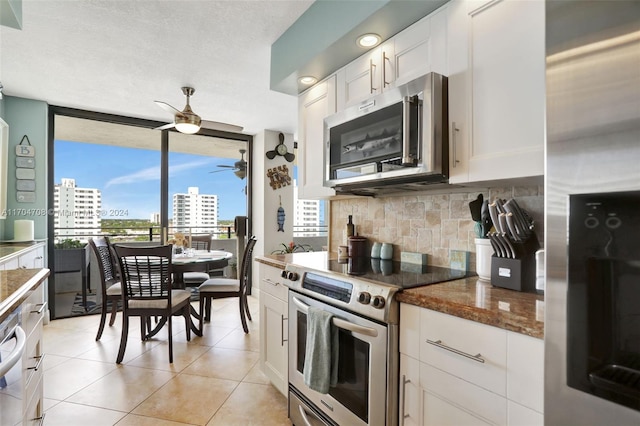 kitchen with appliances with stainless steel finishes, tasteful backsplash, light tile patterned floors, dark stone countertops, and white cabinets