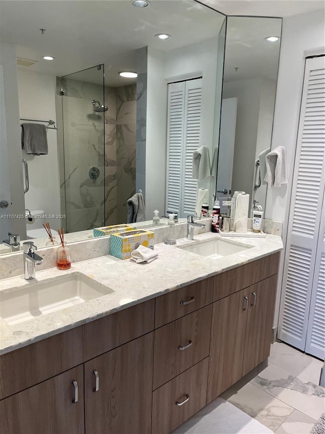 bathroom featuring a closet, marble finish floor, a stall shower, and a sink