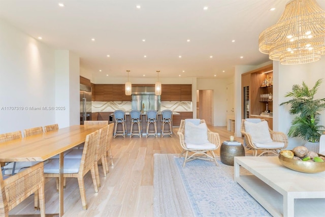 dining room with light wood-type flooring, a chandelier, and recessed lighting