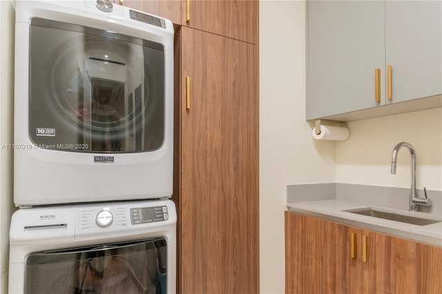 laundry room with a sink, stacked washer and clothes dryer, and cabinet space