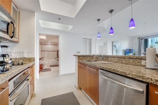 kitchen with light stone countertops, sink, hanging light fixtures, stainless steel appliances, and light tile patterned flooring