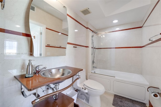 full bathroom featuring tile patterned floors, sink, tiled shower / bath combo, toilet, and tile walls