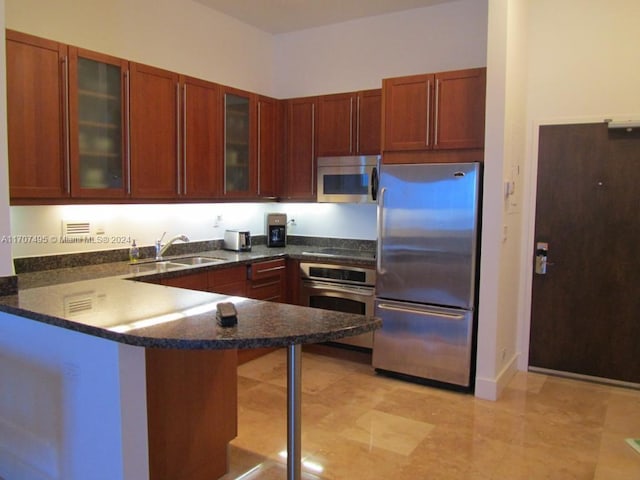 kitchen featuring dark stone counters, sink, a kitchen bar, kitchen peninsula, and stainless steel appliances