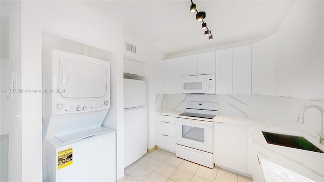 kitchen featuring white cabinetry, sink, light stone counters, stacked washer / dryer, and white appliances