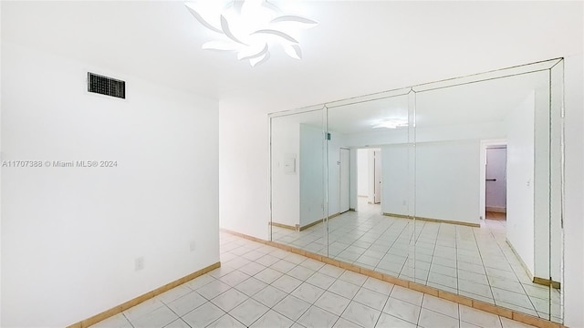 tiled spare room featuring an inviting chandelier