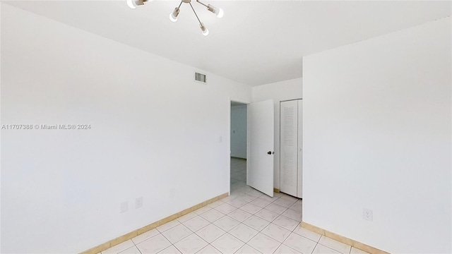 tiled empty room with a chandelier