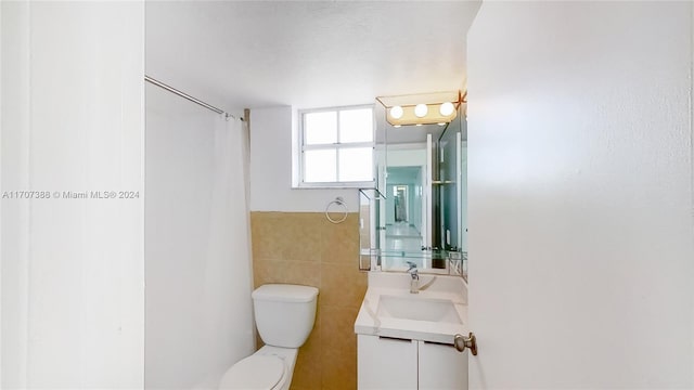 bathroom with vanity, tile walls, and toilet