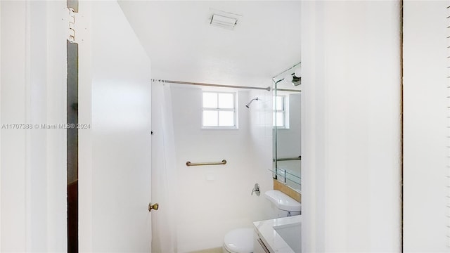 bathroom with a tile shower and toilet