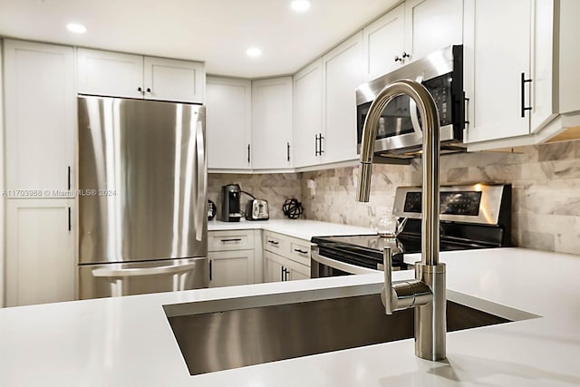 kitchen featuring appliances with stainless steel finishes, backsplash, and white cabinetry