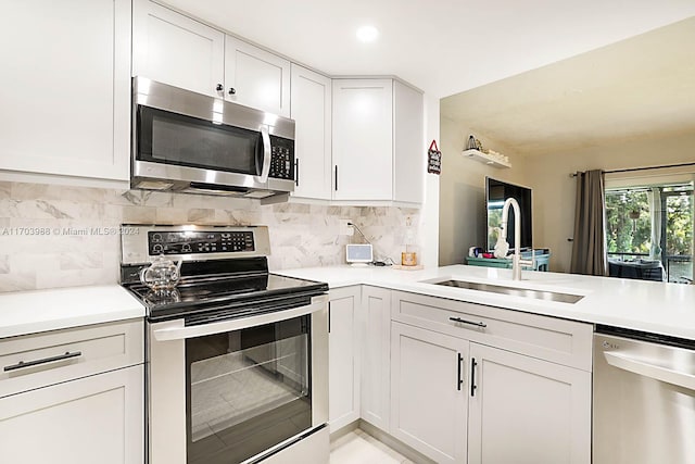 kitchen with backsplash, sink, white cabinets, and stainless steel appliances