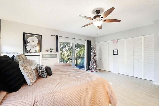 bedroom featuring ceiling fan, access to exterior, a textured ceiling, light hardwood / wood-style floors, and multiple closets