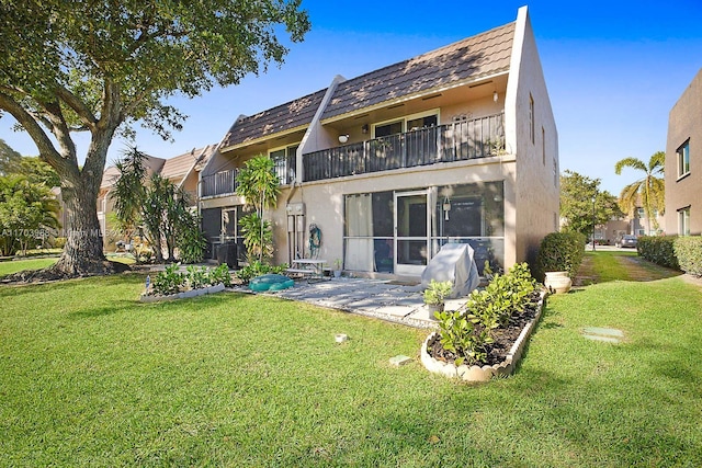 back of house featuring a balcony, a yard, and a patio