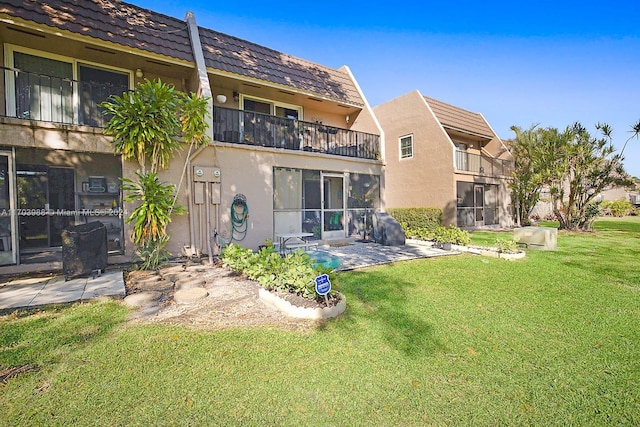 back of house featuring a patio area, a yard, and a balcony