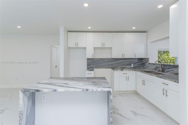 kitchen with sink, backsplash, white cabinets, and light stone counters