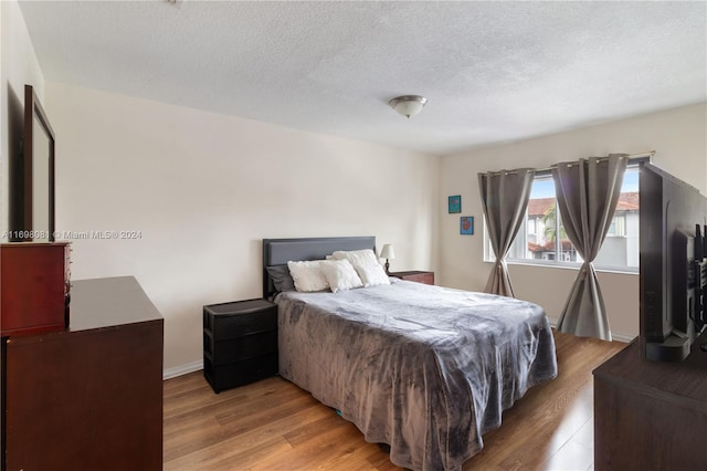 bedroom with light hardwood / wood-style floors and a textured ceiling